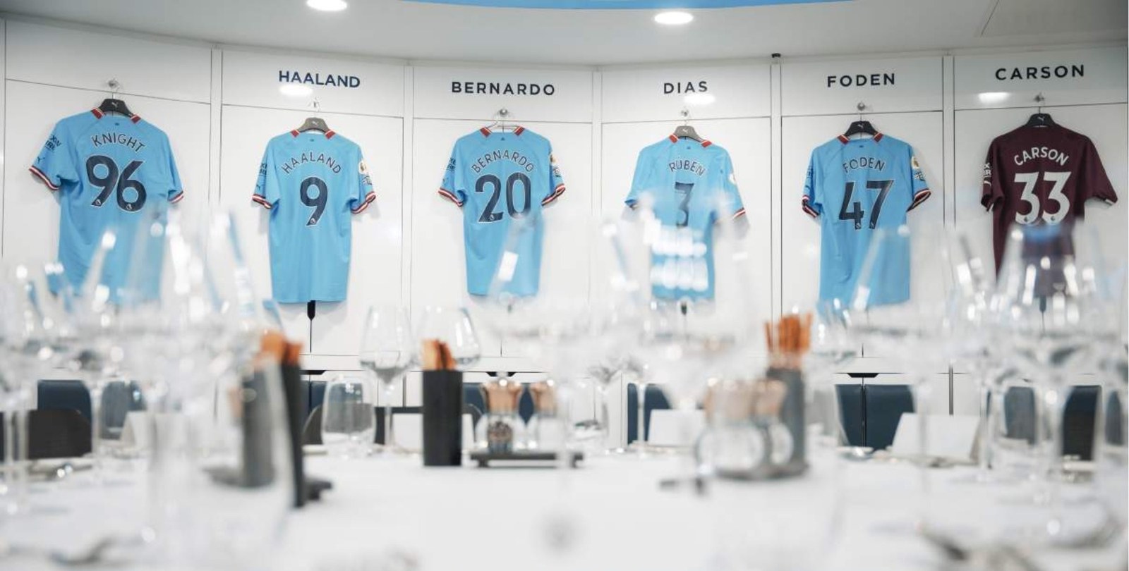 The Manchester City dressing room laid for dinner beneath the players shirts