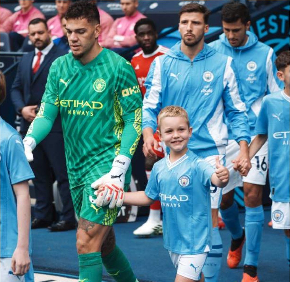 A Manchester City mascot walking out with the goalkeeper at the Etihad Stadium