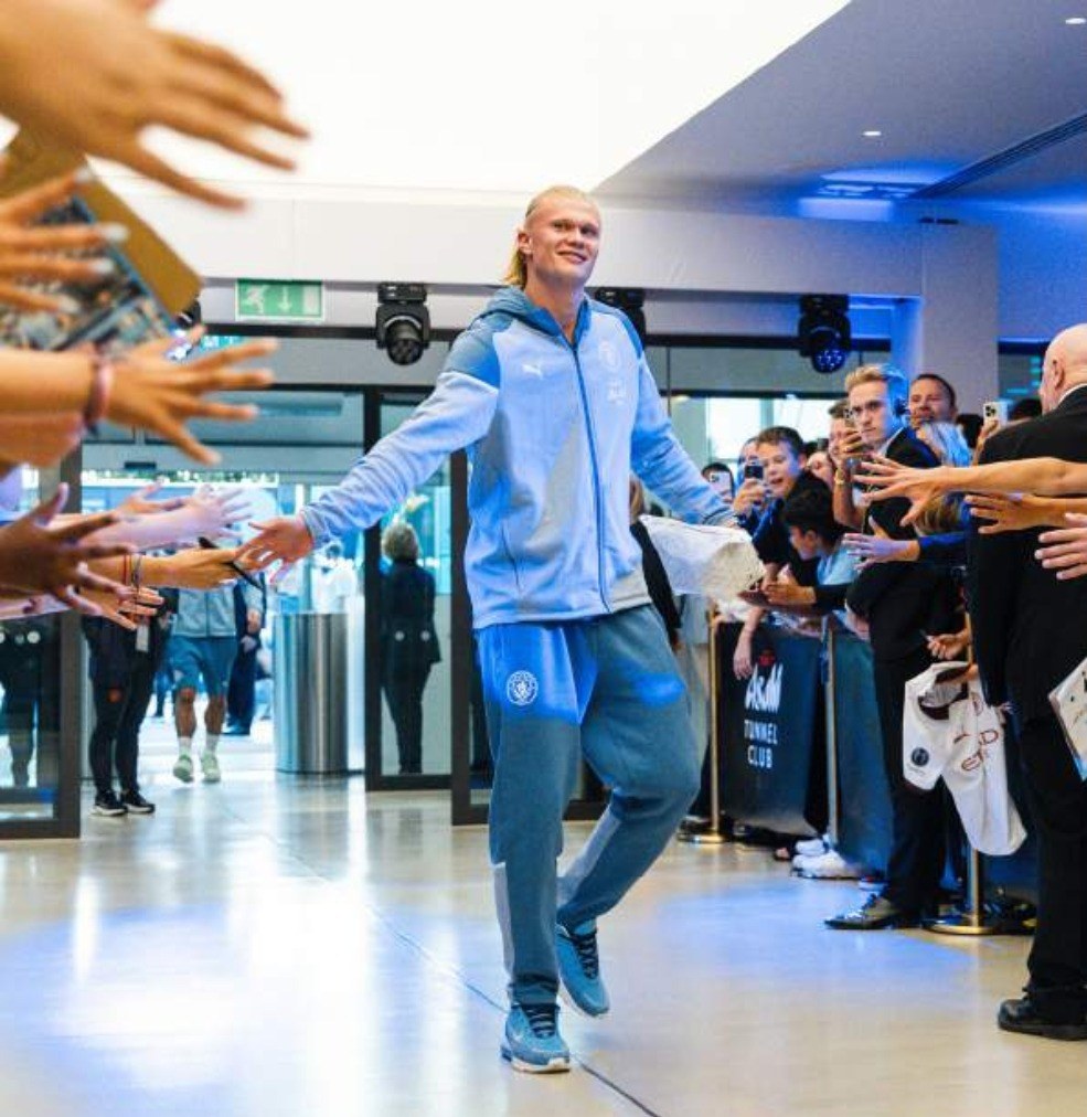 A Manchester City player arriving through a guard of honour of supporters