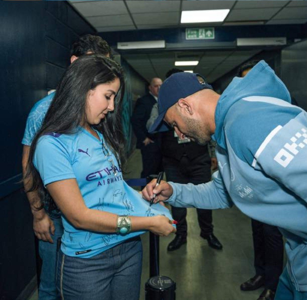 A Manchester City player signing a supporters shirt