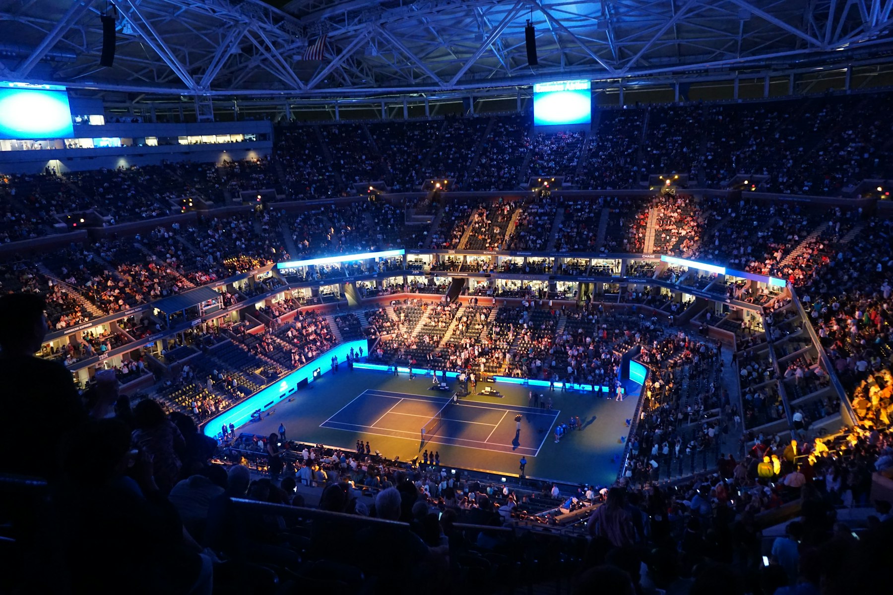 A floodlit tennis court during an evening session